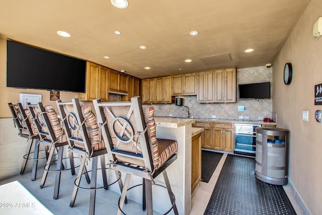 kitchen with light stone countertops, light tile patterned floors, tasteful backsplash, and beverage cooler