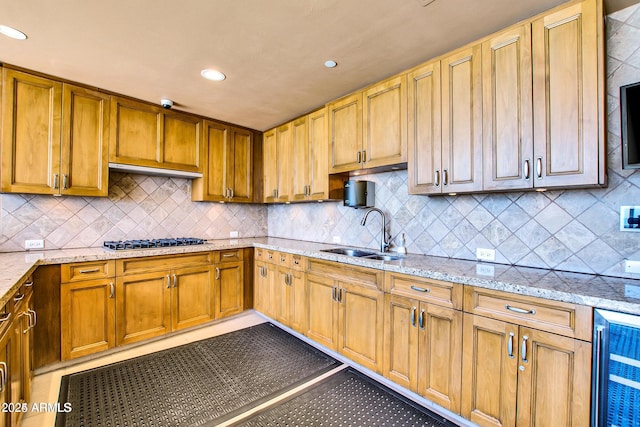 kitchen featuring decorative backsplash, sink, beverage cooler, and stainless steel gas cooktop