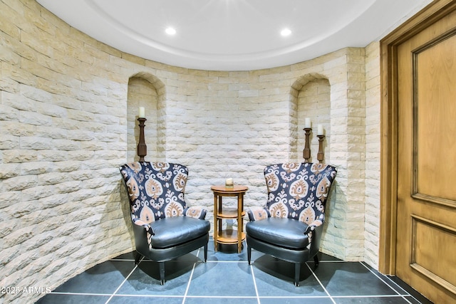 sitting room with tile patterned flooring and brick wall