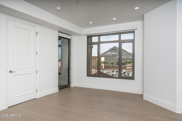 unfurnished room featuring a mountain view and light hardwood / wood-style floors