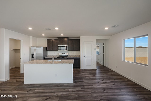 kitchen with dark brown cabinetry, dark hardwood / wood-style flooring, an island with sink, and stainless steel appliances