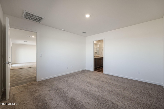 unfurnished bedroom featuring dark colored carpet and connected bathroom