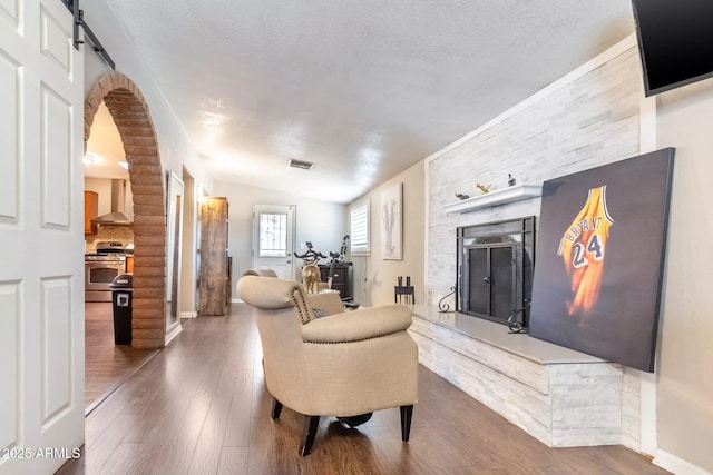 living room featuring visible vents, baseboards, arched walkways, and wood finished floors