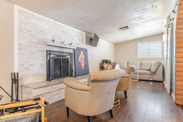 living area featuring a fireplace, wood-type flooring, visible vents, and lofted ceiling