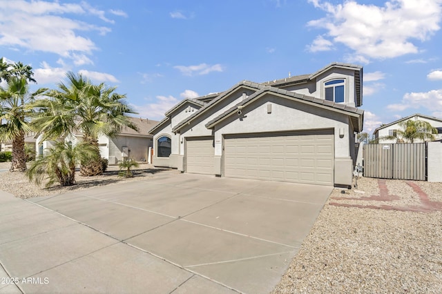 view of front of home with concrete driveway, a tiled roof, an attached garage, a gate, and stucco siding