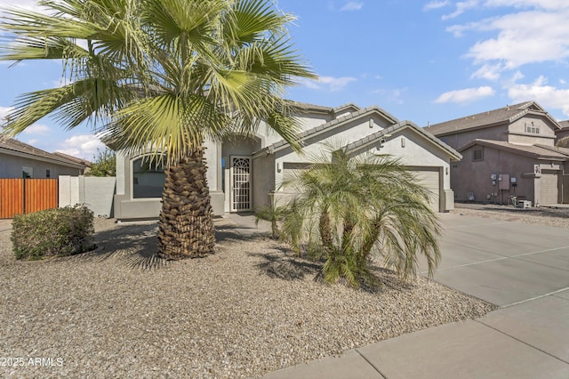 view of front of property featuring an attached garage, fence, concrete driveway, and stucco siding