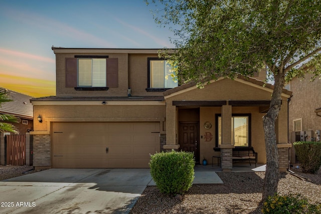 traditional-style house featuring stucco siding, an attached garage, driveway, covered porch, and brick siding
