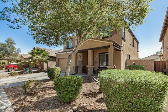 view of front facade featuring stone siding, fence, concrete driveway, stucco siding, and a porch