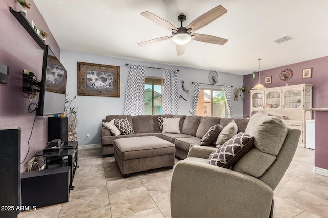 living area with baseboards, ceiling fan, and visible vents