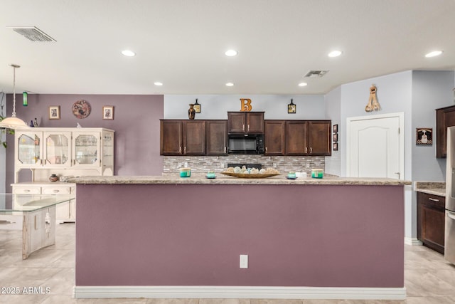 kitchen with visible vents, black microwave, dark brown cabinets, and tasteful backsplash