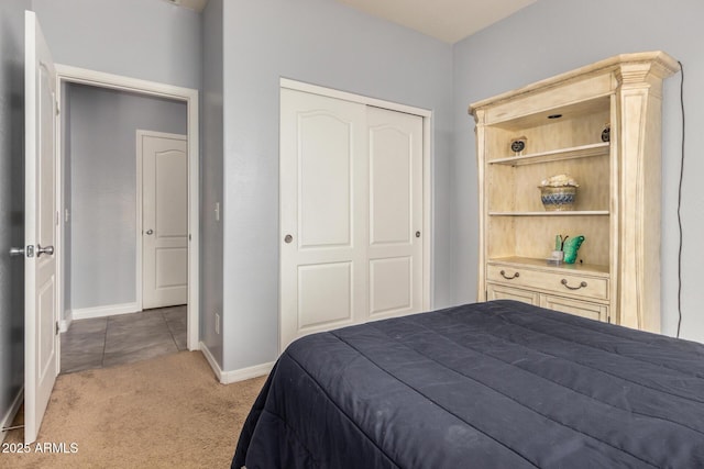 carpeted bedroom with a closet and baseboards