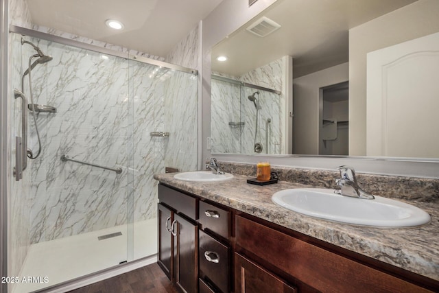 full bath featuring double vanity, visible vents, a sink, and a marble finish shower