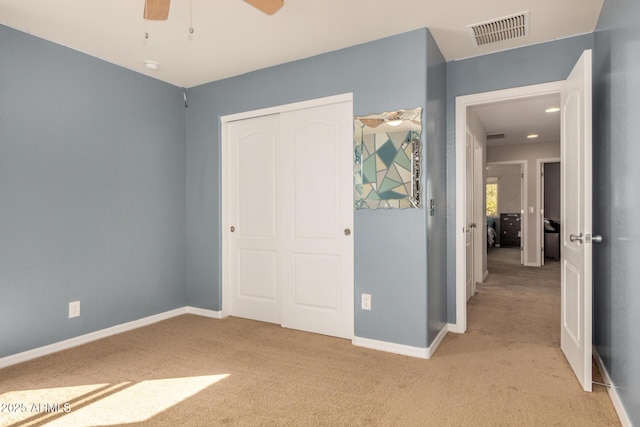 unfurnished bedroom featuring light colored carpet, visible vents, a closet, and baseboards