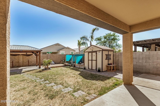 view of yard featuring a fenced backyard, an outbuilding, a storage unit, and a patio