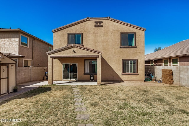 rear view of house with a fenced backyard, stucco siding, an outbuilding, a yard, and a patio area