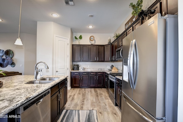 kitchen with sink, hanging light fixtures, dark brown cabinets, stainless steel appliances, and light stone countertops