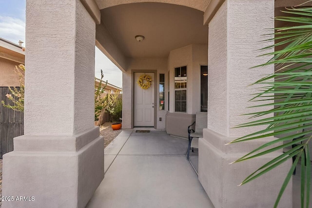 view of exterior entry featuring fence and stucco siding