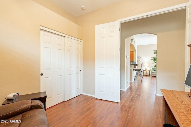 interior space with arched walkways, wood finished floors, and baseboards