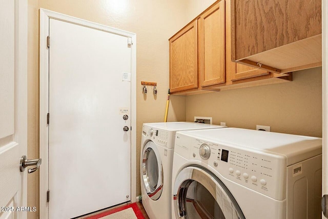 washroom featuring cabinet space and washer and clothes dryer