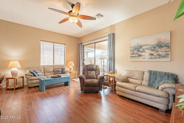 living area with ceiling fan, wood finished floors, and visible vents