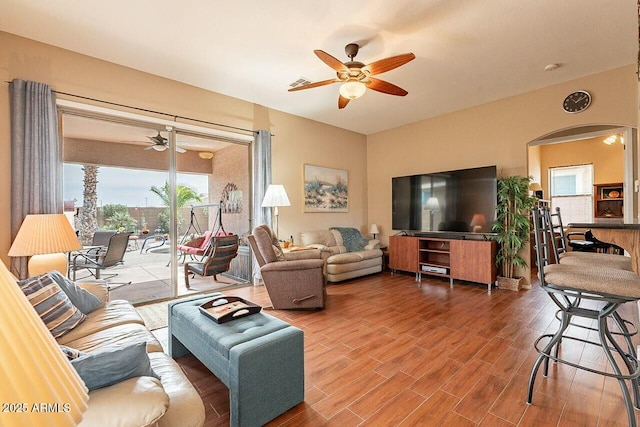 living area featuring arched walkways, visible vents, wood finished floors, and a ceiling fan