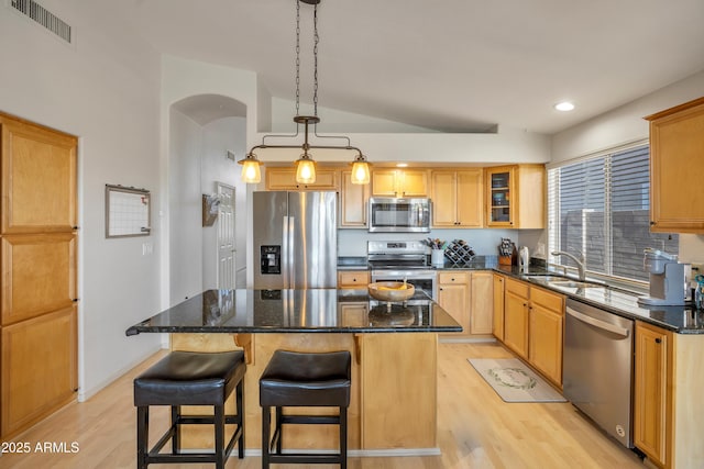 kitchen with arched walkways, a sink, visible vents, appliances with stainless steel finishes, and a center island