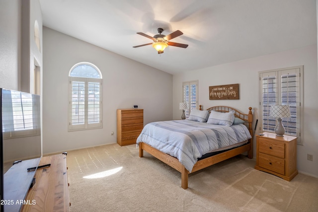 bedroom with a ceiling fan, light colored carpet, and vaulted ceiling