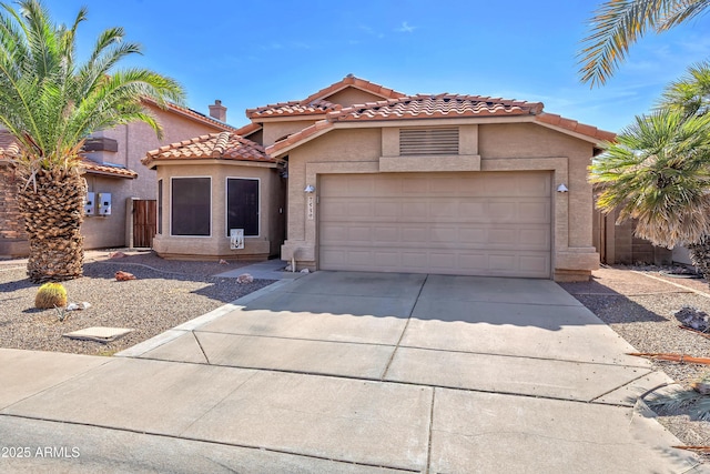 mediterranean / spanish house featuring a garage, a tile roof, driveway, and stucco siding