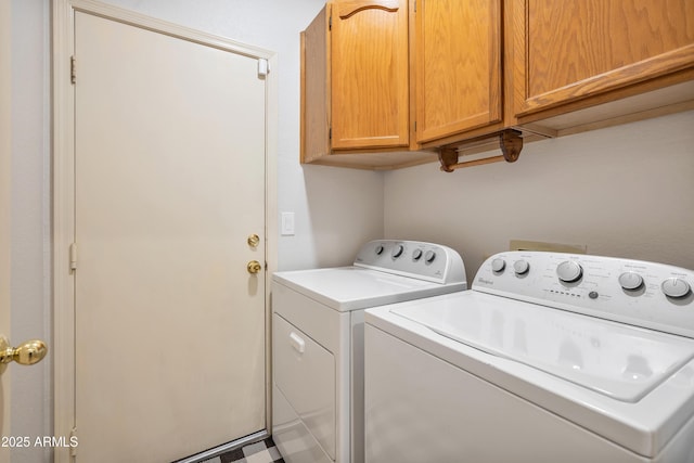 clothes washing area featuring washing machine and dryer and cabinet space