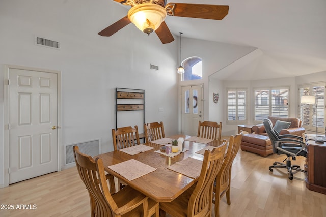 dining room featuring high vaulted ceiling, light wood-style flooring, and visible vents