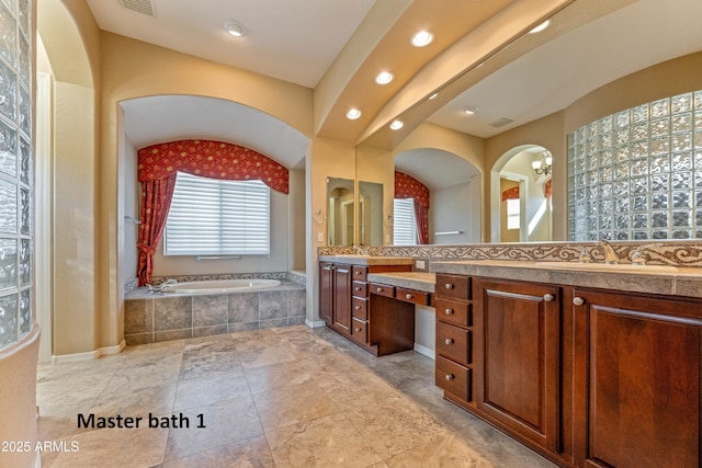 bathroom with tiled bath and vanity