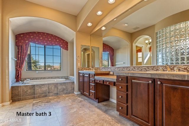 bathroom with a relaxing tiled tub and vanity