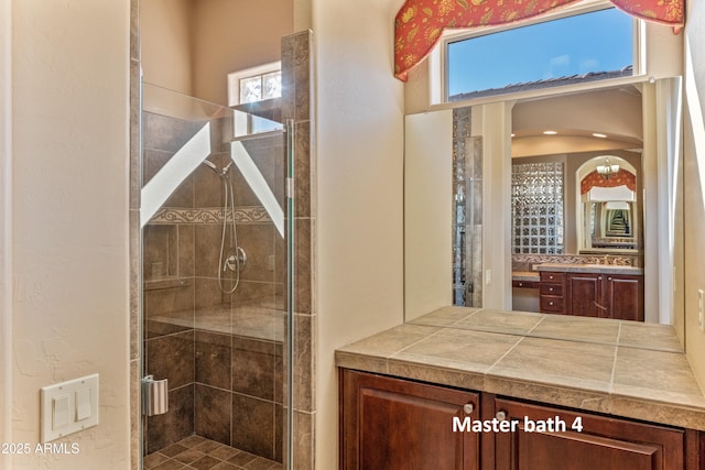 bathroom with a shower with shower door, vanity, and tasteful backsplash