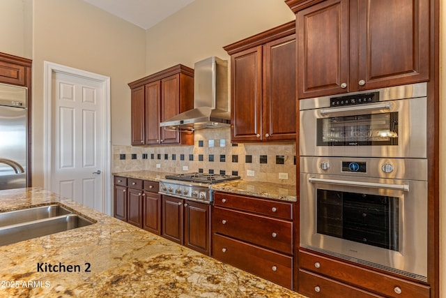 kitchen featuring backsplash, sink, appliances with stainless steel finishes, wall chimney exhaust hood, and light stone counters