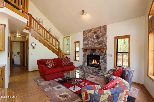 9434 W Obier Dr, Pine, AZ 85544 - living room featuring light wood-style flooring, stairs, a stone fireplace, high vaulted ceiling, and baseboards