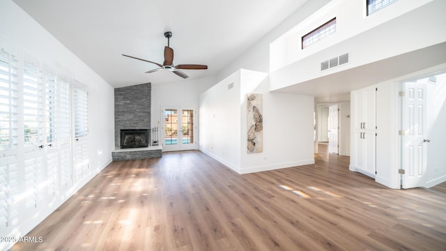 unfurnished living room featuring hardwood / wood-style floors, a fireplace, french doors, high vaulted ceiling, and ceiling fan