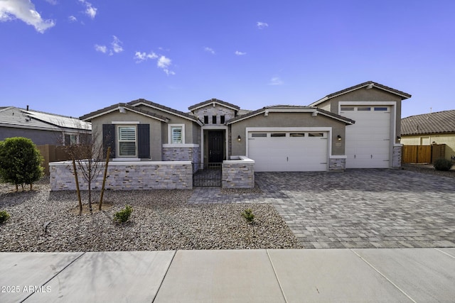 view of front facade with a garage, decorative driveway, fence, and stucco siding