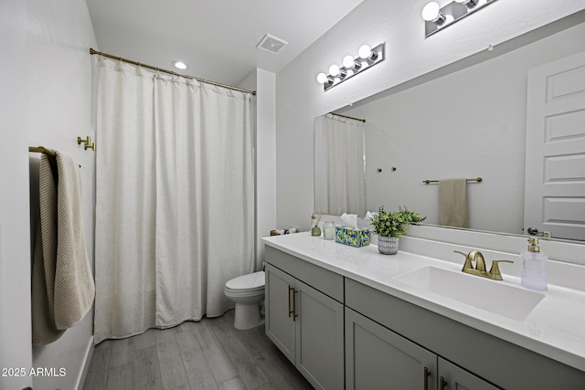 bathroom featuring toilet, visible vents, wood finished floors, and vanity