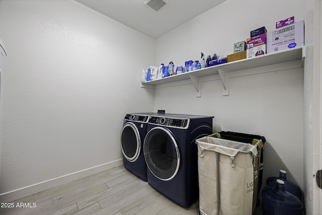 washroom with laundry area, visible vents, baseboards, light wood-style flooring, and washer and dryer