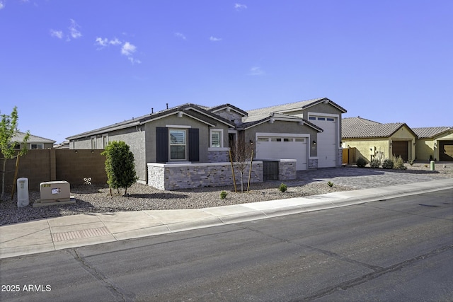 view of front facade featuring stone siding, an attached garage, fence, and stucco siding