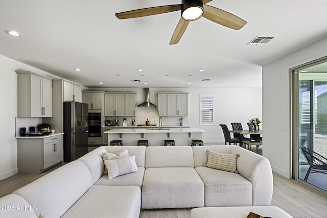 living room featuring light wood-style flooring, visible vents, and recessed lighting