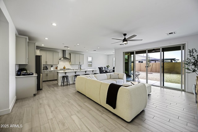 living area with a ceiling fan, recessed lighting, visible vents, and light wood finished floors