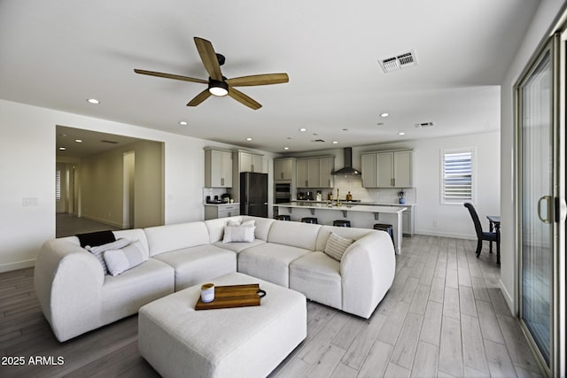 living area with light wood finished floors, visible vents, and recessed lighting