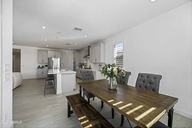 dining space featuring light wood finished floors, baseboards, visible vents, and recessed lighting