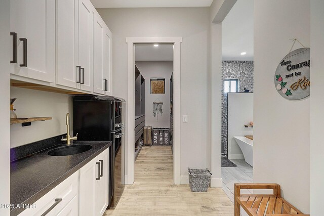 26112 N 7th Ave, Phoenix, AZ 85085 - kitchen featuring a sink, light wood-style flooring, white cabinets, freestanding refrigerator, and dark stone counters