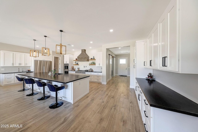 26112 N 7th Ave, Phoenix, AZ 85085 - kitchen featuring stainless steel appliances, dark countertops, a sink, light wood-style floors, and a breakfast bar area