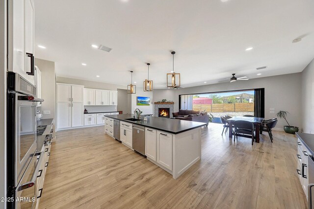26112 N 7th Ave, Phoenix, AZ 85085 - kitchen featuring dark countertops, open floor plan, ceiling fan, a lit fireplace, and white cabinetry
