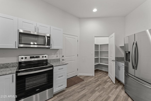 kitchen featuring light stone counters, recessed lighting, stainless steel appliances, light wood-style floors, and white cabinetry