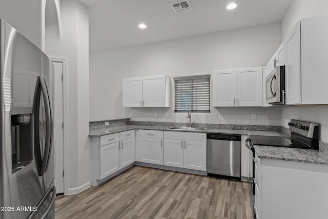 kitchen featuring visible vents, light wood-style flooring, a sink, appliances with stainless steel finishes, and white cabinets