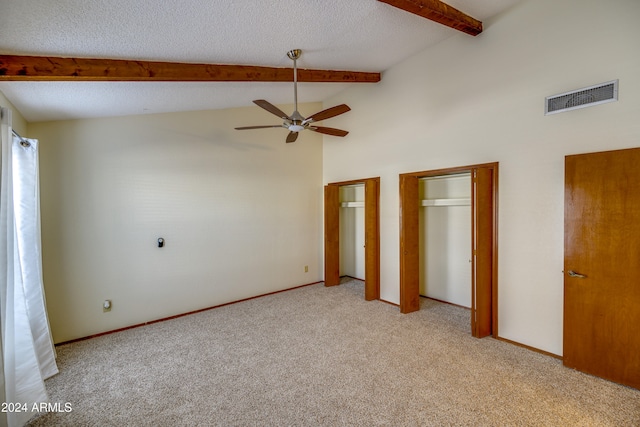 unfurnished bedroom featuring light colored carpet, ceiling fan, high vaulted ceiling, beamed ceiling, and multiple closets